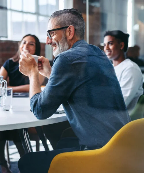 Cheerful mature businessman attending a meeting with his colleagues